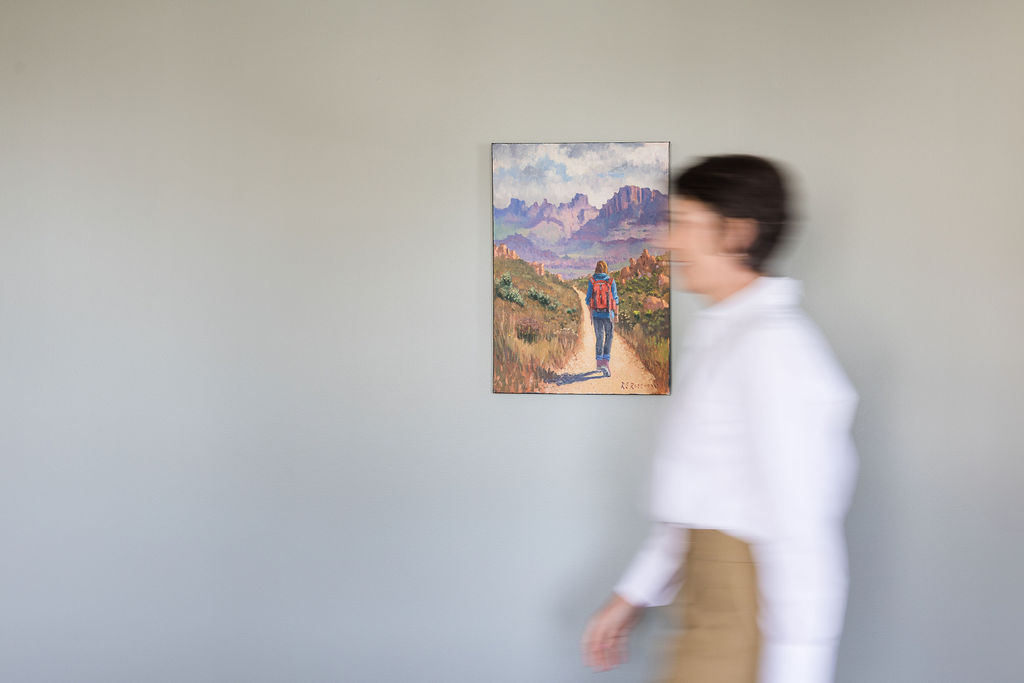 Dr Maretha Rossouw walking past a landscape painting in the practice